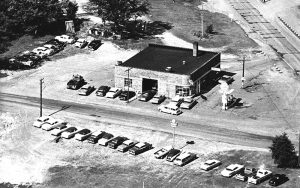 old black and white photo of chevy garage with cars outside